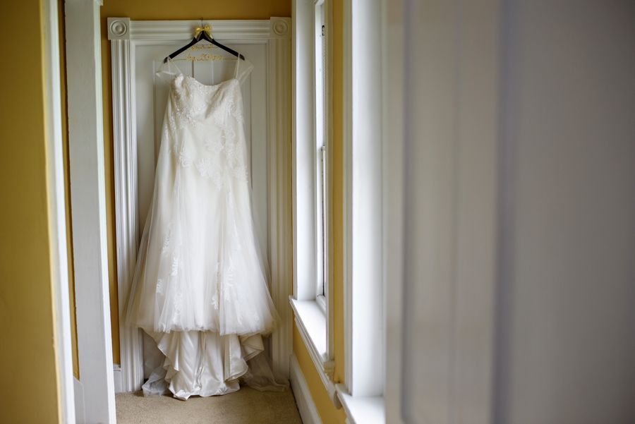 A brides wedding dress hanging in the hallway on the morning of the wedding.